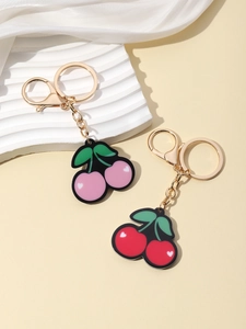 Detail view of pink and red cherry keychains on a white wave platform with silk