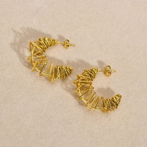 Macro shot of gold-plated twisted C-ring earrings with textured wire-wrapped design