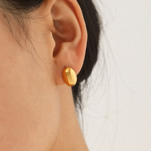 Polished gold titanium steel oval stud earrings shown on model for size and elegant fit
