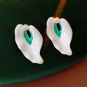 Macro detail of vintage enamel petal earrings with a green center and small white pearl
