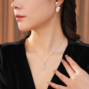 Detail of flower necklace and pearl drop earrings set with crystals in gold finish