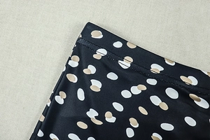 Detailed close-up of double-needle stitching on black polka dot printed fabric