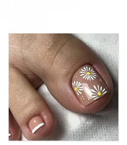 Close-up of nude pink press-on toenails featuring white daisy art and French tips