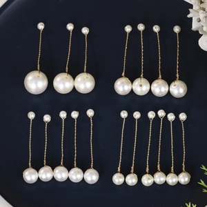 Detailed view of handmade pearl hairpins and earrings on a navy plate for weddings