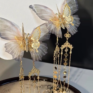 Macro shot of golden butterfly hair clip with layered wings and long chain tassels