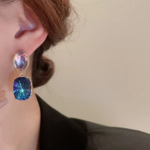 Detail view of double stone earrings featuring purple oval and dark blue rectangle gems