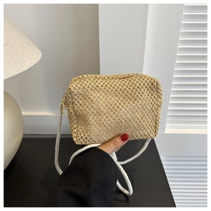 Detail of hand-woven straw crossbody bag with white cotton strap and zipper closure