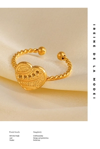 Detail of 18K gold-plated heart ring with textured engravings on warm silk background