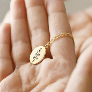 Detailed shot of golden vintage oval floral pendant with intricate botanical engraving