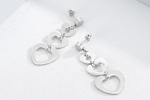 Détail de boucles d'oreilles pendantes en acier titane avec triple cœur évidé argenté