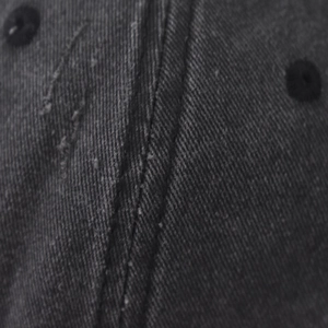 Macro shot of washed canvas texture and vintage distressed stitching on baseball cap