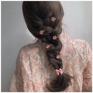 Detail showing small pink peach and bow hair clips styled on a braided hairstyle