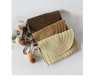 Straw envelope clutch bags in three earthy tones with decorative pompom tassels and straps