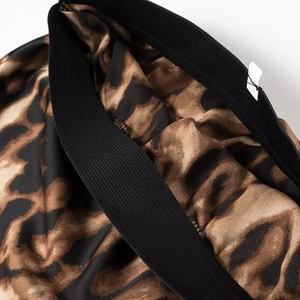 Detailed close-up of leopard print satin fabric with high-elastic black waistband