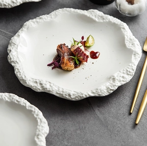 Primo piano di un piatto in ceramica bianca con un bordo unico con trama di roccia
