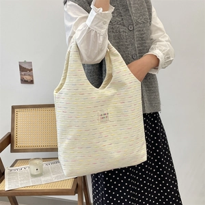 Detail shot of white woven tote bag with colorful texture and stylish brand label