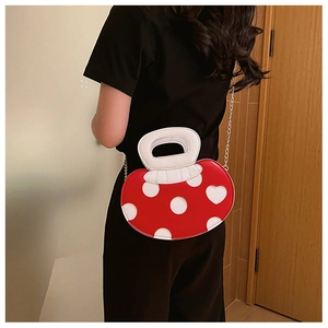 Detail of red mushroom pattern crossbody bag with white chain strap shown on model's back