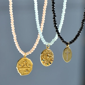 Close-up of bohemian necklaces with colorful beads and gold evil eye coin pendants