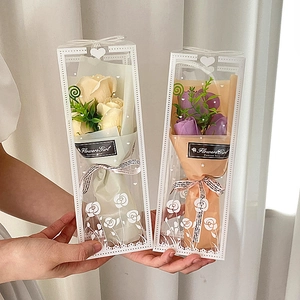 Close-up of champagne and purple soap rose bouquets in elegant transparent gift boxes