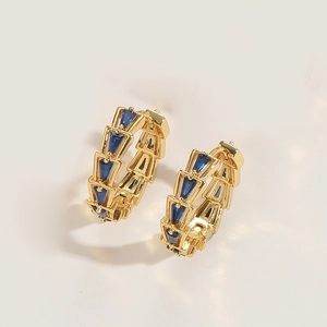 Detail view of gold-plated geometric hoop earrings with deep blue trapezoid stones