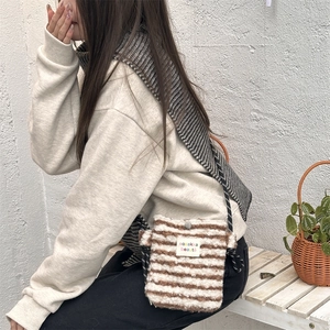 Detail of plush striped crossbody bag featuring a soft texture and woven shoulder strap