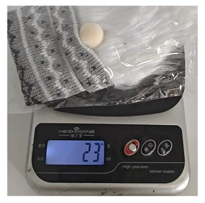 Close-up showing a grey knitted Christmas bottle cover weighing 23g on a digital scale