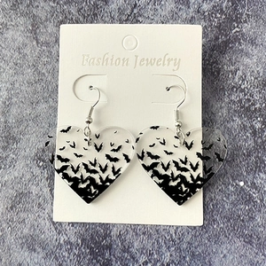 Halloween bat acrylic heart earrings displayed on grey rock textured background
