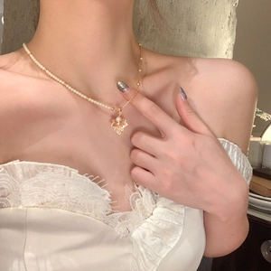 Détail du collier à pendentif feuille d'érable avec perles et chaîne dorée sur le cou