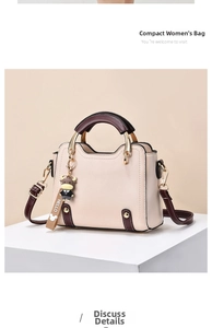 Detail of cream and brown crossbody bag with gold hardware and cartoon cow charm