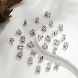 Detailed view of 18k silver alphabet and heart beads with micro-pave zircons on wood