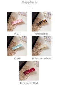 Detail of five colorful acetate hair clips with pearl accents on a white lace background