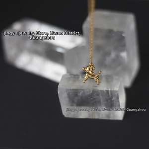 Macro view of a 18K gold-plated balloon dog pendant on a delicate chain necklace