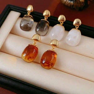 Detailed shot of three pairs of 18K gold-plated resin earrings in a black jewelry box