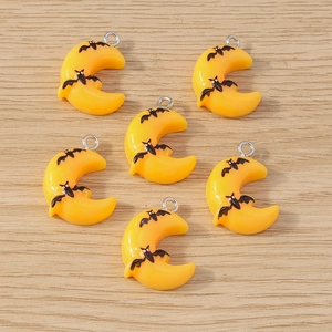 Detail of yellow resin moon pendants with black bat motifs and metal loops for jewelry