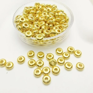 Close-up of golden round alloy spacer beads for DIY jewelry making in clear storage box