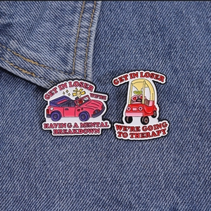 Detail of funny enamel car pins with text on blue denim background fabric