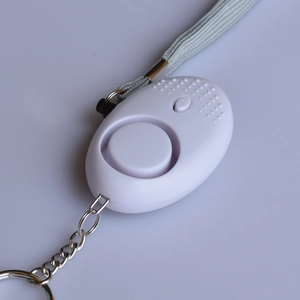 White personal safety alarm with metal keychain and braided lanyard shown from top view