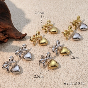 Set of 18K gold plated bow and heart drop earrings on a rustic background