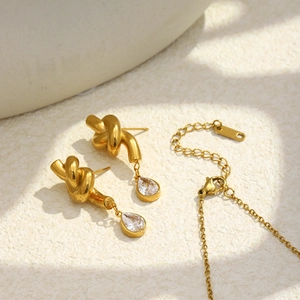 Macro view of 18K gold-plated knotted jewelry set with sparkling water-drop zircons