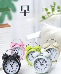 Detailed close-up of retro twin bell alarm clocks in assorted pastel matte finishes