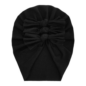 Detail of a soft black cotton baby turban hat featuring three decorative bows and knit texture