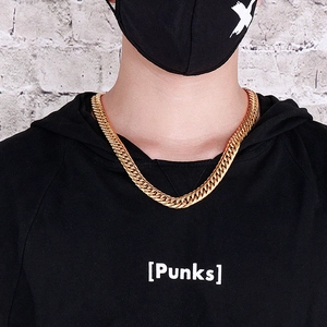 Close-up of a chunky golden Cuban link chain necklace worn on a street style model