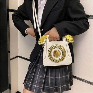 Detail of vintage telephone-shaped white leather handbag with golden dial on a model