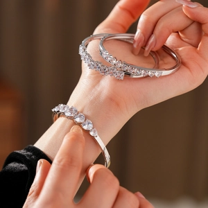 Gros plan sur trois bracelets en argent poli ornés de zircons en forme de cœur et carrés