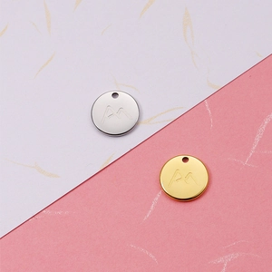 Macro view of gold and silver stainless steel mountain engraved circular charms