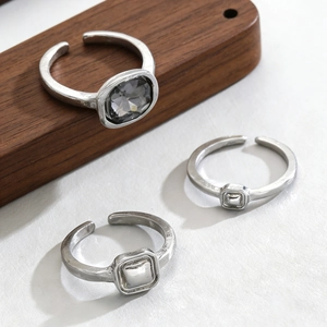 Detail view of silver alloy ring set with dark grey faceted stone on white leather