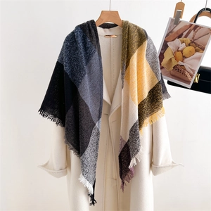 Detail of colorful plaid cashmere-like scarf with fringe on a white wool coat