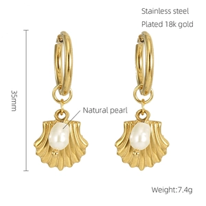 Macro detail of 18k gold plated earrings featuring natural pearl and shell pendants