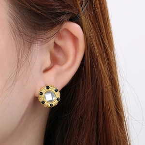 Détail d'une boucle d'oreille vintage en or 18K avec perles noires et cristal carré