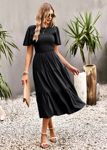 Detail of black mid-length dress featuring a smocked bodice and layered tiered skirt